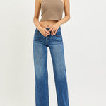 Woman wearing a beige halter top and blue jeans on a white background