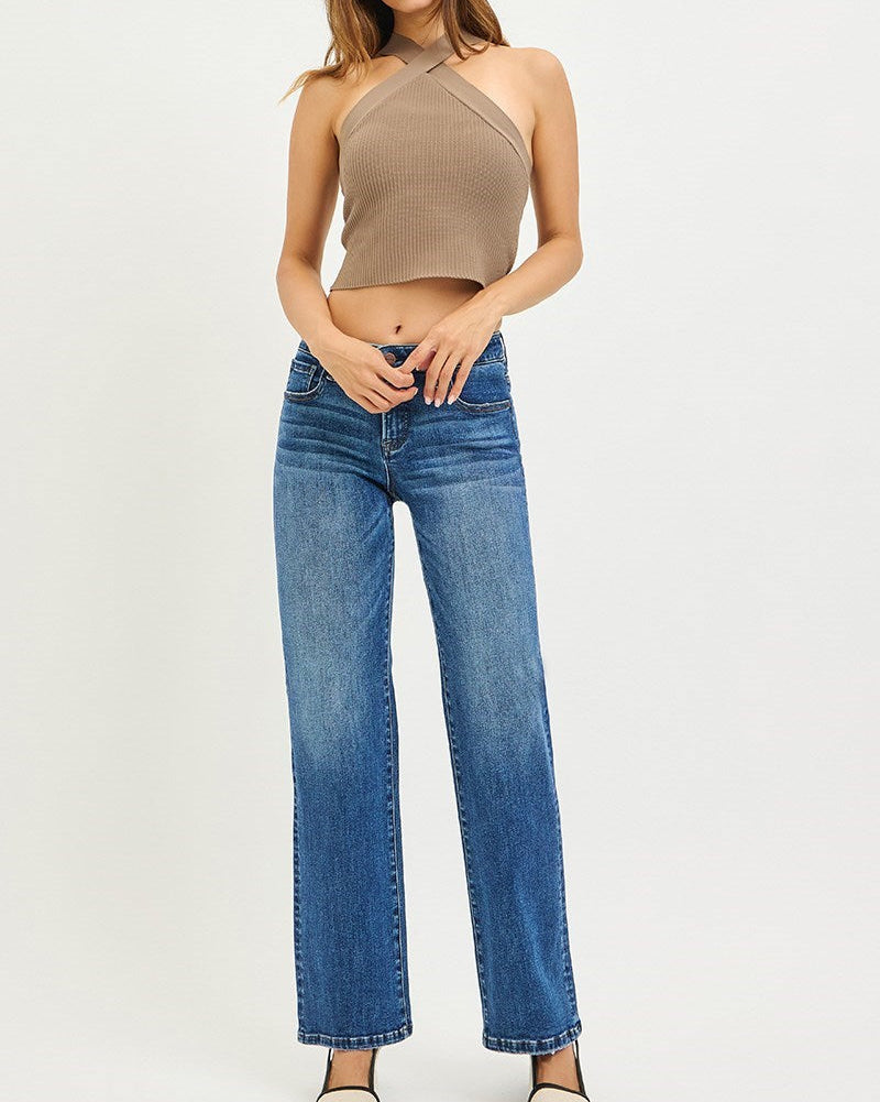 Woman wearing a beige halter top and blue jeans on a white background