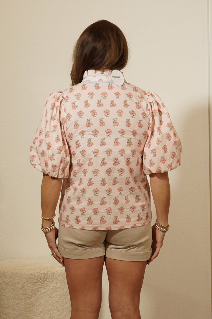 Person wearing a pink patterned shirt and beige shorts standing in front of a mirror.
