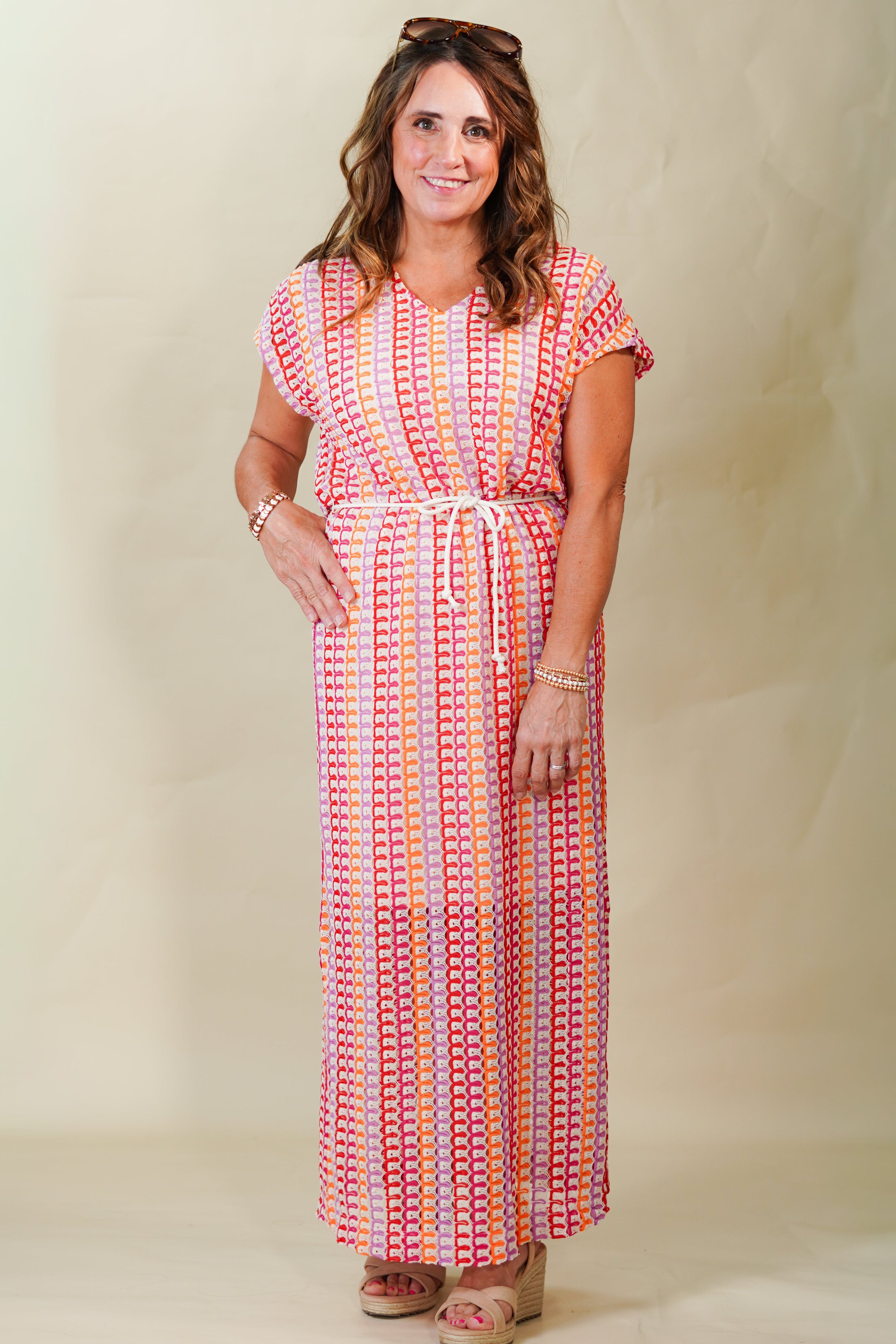 Woman wearing a colorful patterned dress against a plain background