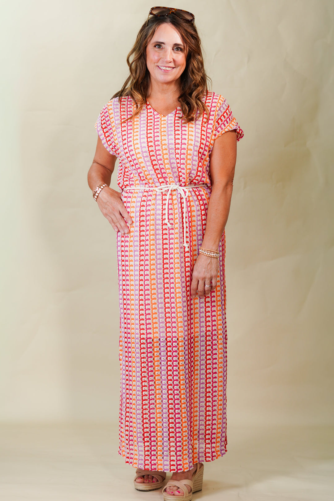 Woman wearing a colorful patterned dress against a plain background