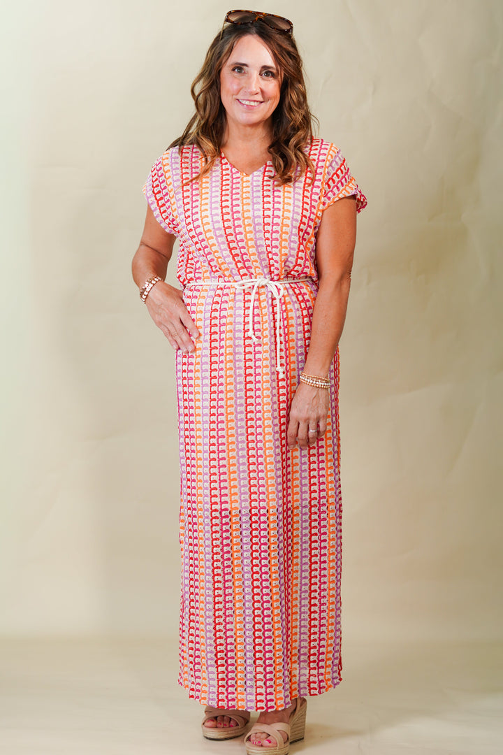 Woman wearing a colorful patterned dress against a plain background