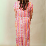 Woman wearing a colorful patterned dress against a plain background