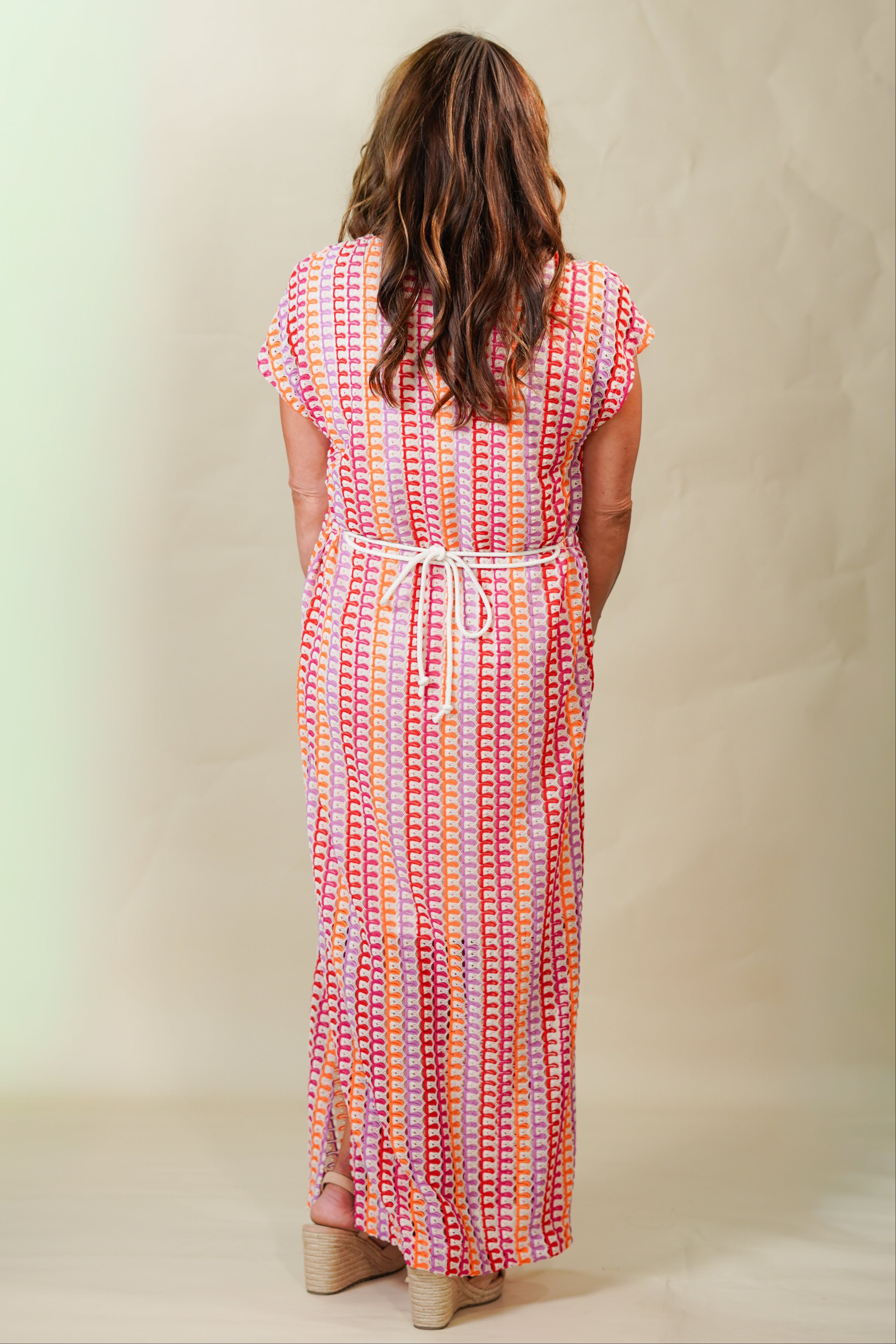 Woman wearing a colorful patterned dress against a plain background