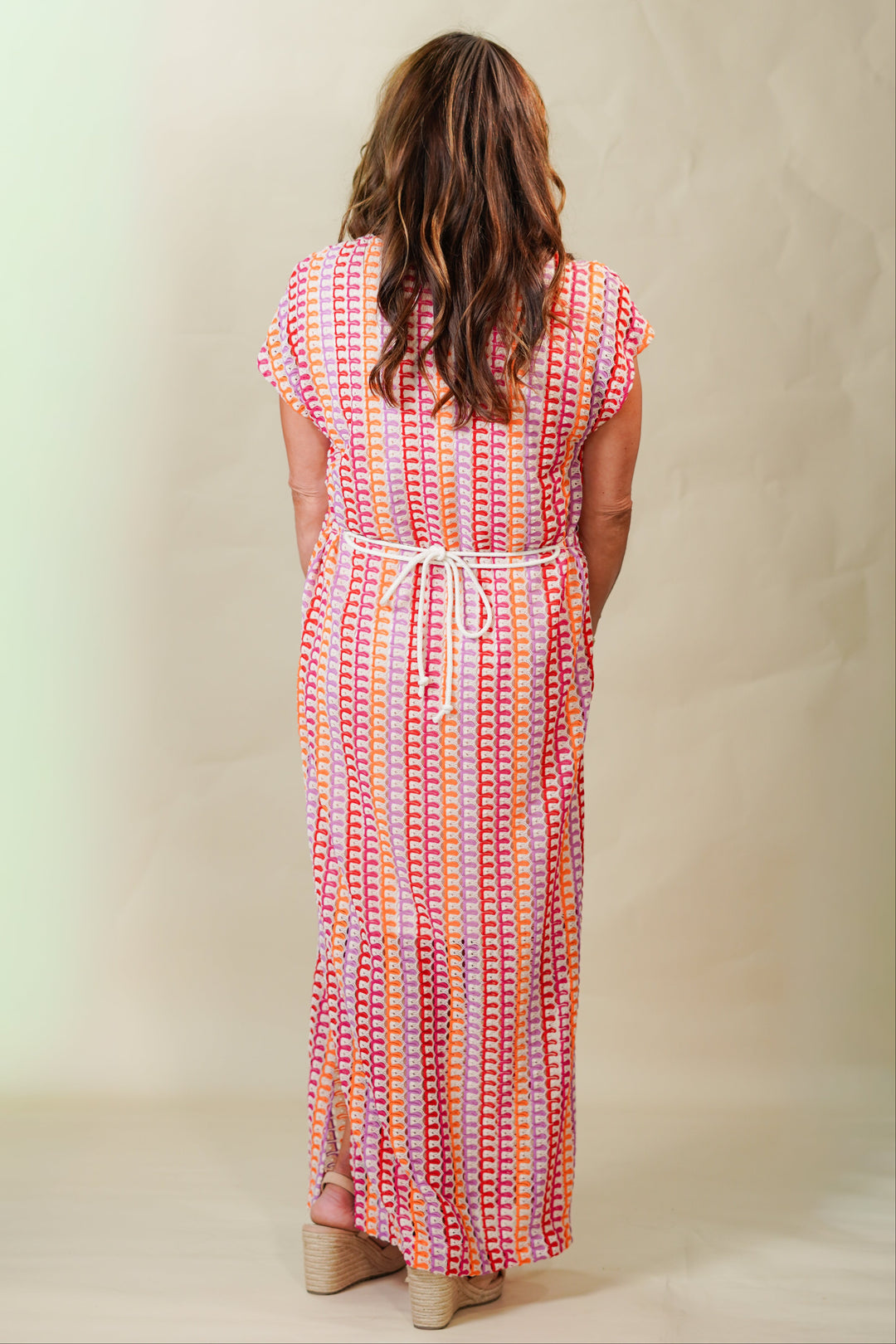 Woman wearing a colorful patterned dress against a plain background