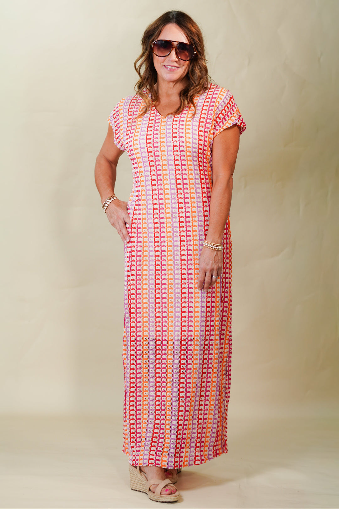 Woman wearing a long, patterned dress against a plain background