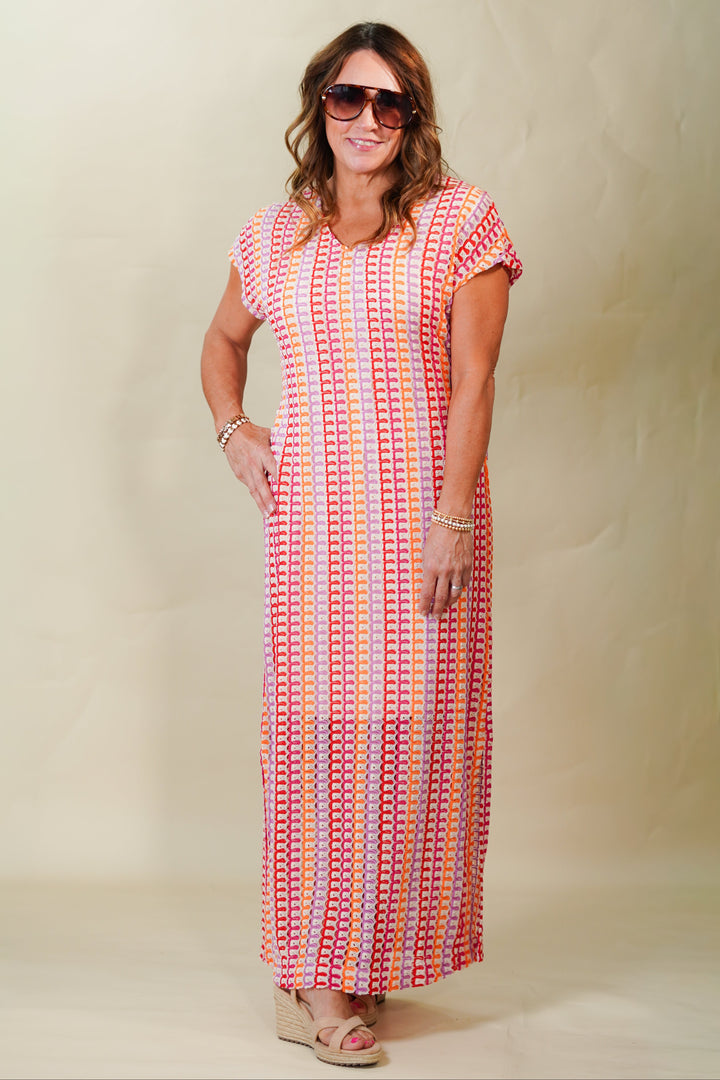 Woman wearing a long, patterned dress against a plain background
