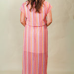 Woman wearing a colorful patterned dress against a plain background