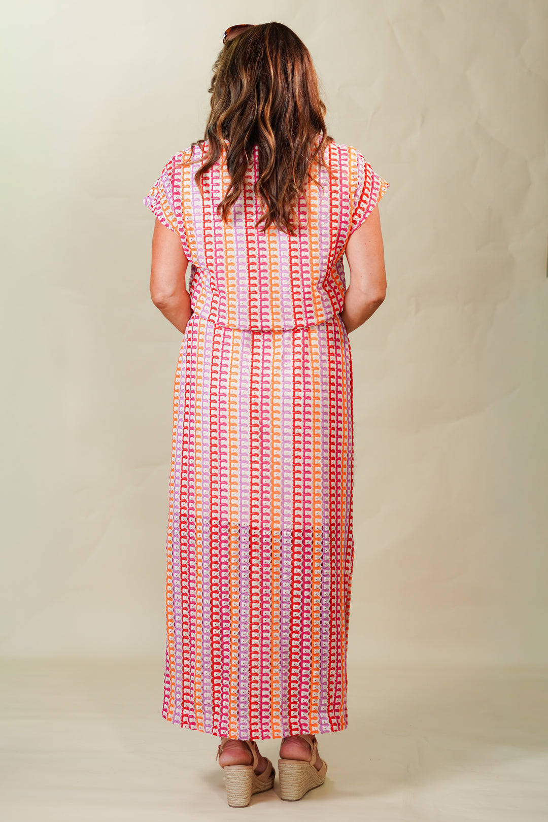 Woman wearing a colorful patterned dress against a plain background