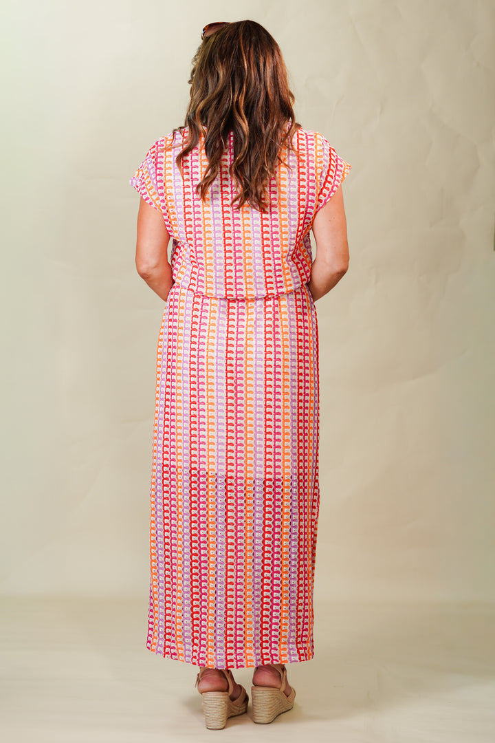 Woman wearing a colorful patterned dress against a plain background