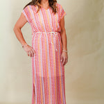 Woman wearing a colorful patterned dress on a plain background