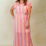 Woman wearing a colorful patterned dress against a plain background