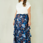 Woman wearing navy floral tiered ruffle maxi skirt with white top
