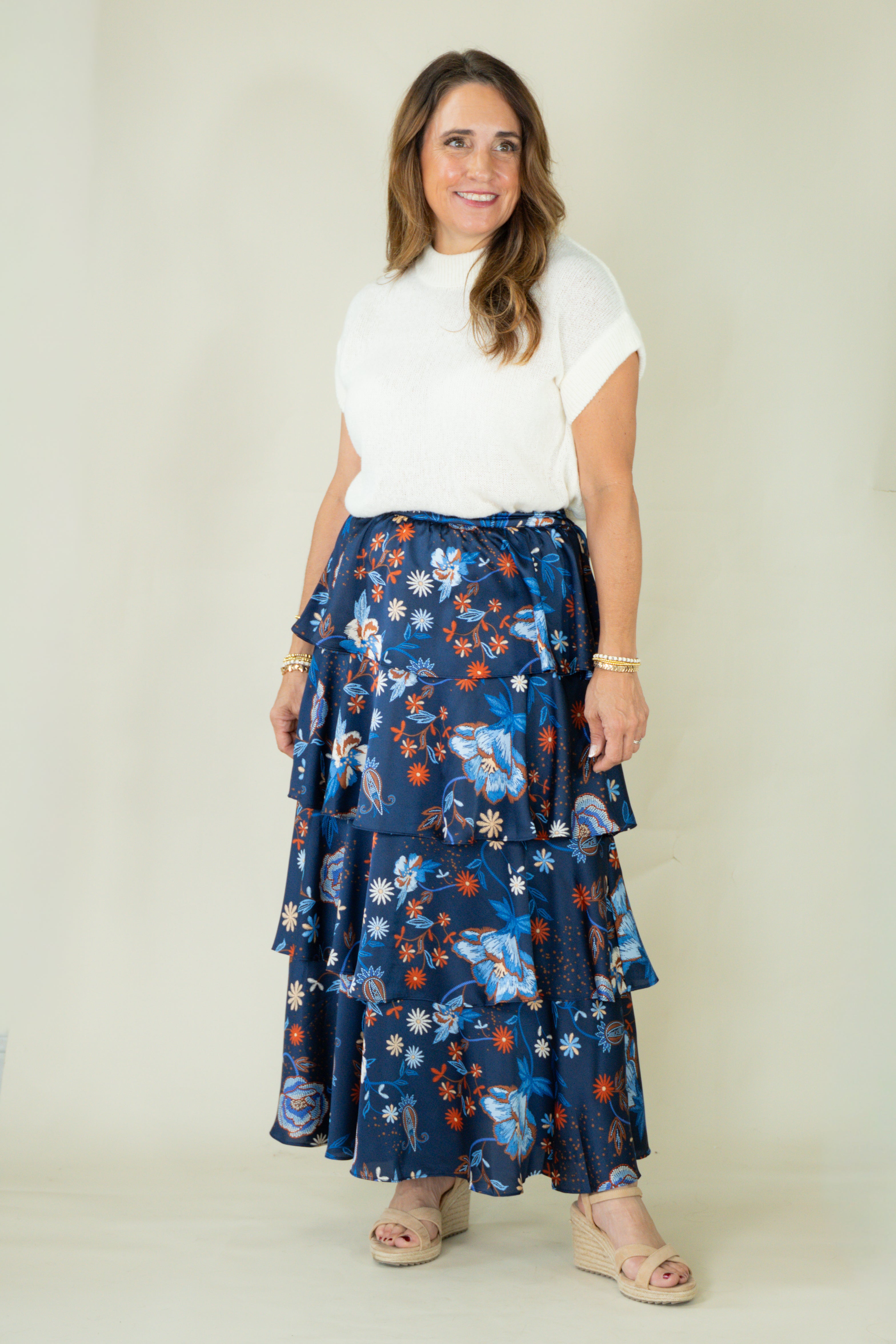Woman wearing navy floral tiered ruffle maxi skirt with white top