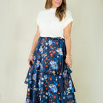 Woman wearing navy floral tiered ruffle maxi skirt with white top