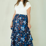 Woman wearing navy floral tiered ruffle maxi skirt with white top
