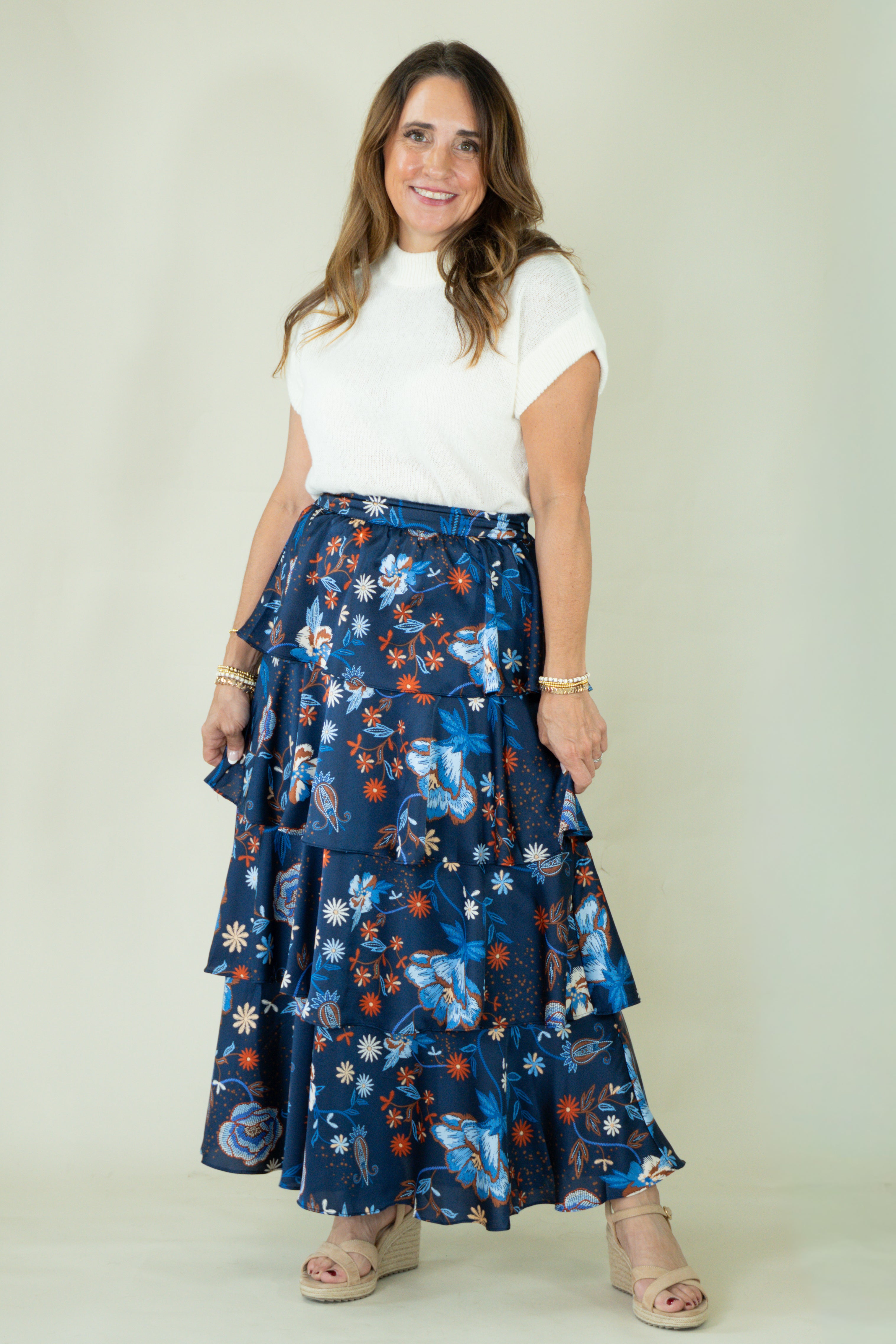 Woman wearing navy floral tiered ruffle maxi skirt with white top