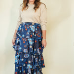 Woman wearing navy floral tiered ruffle maxi skirt with taupe top