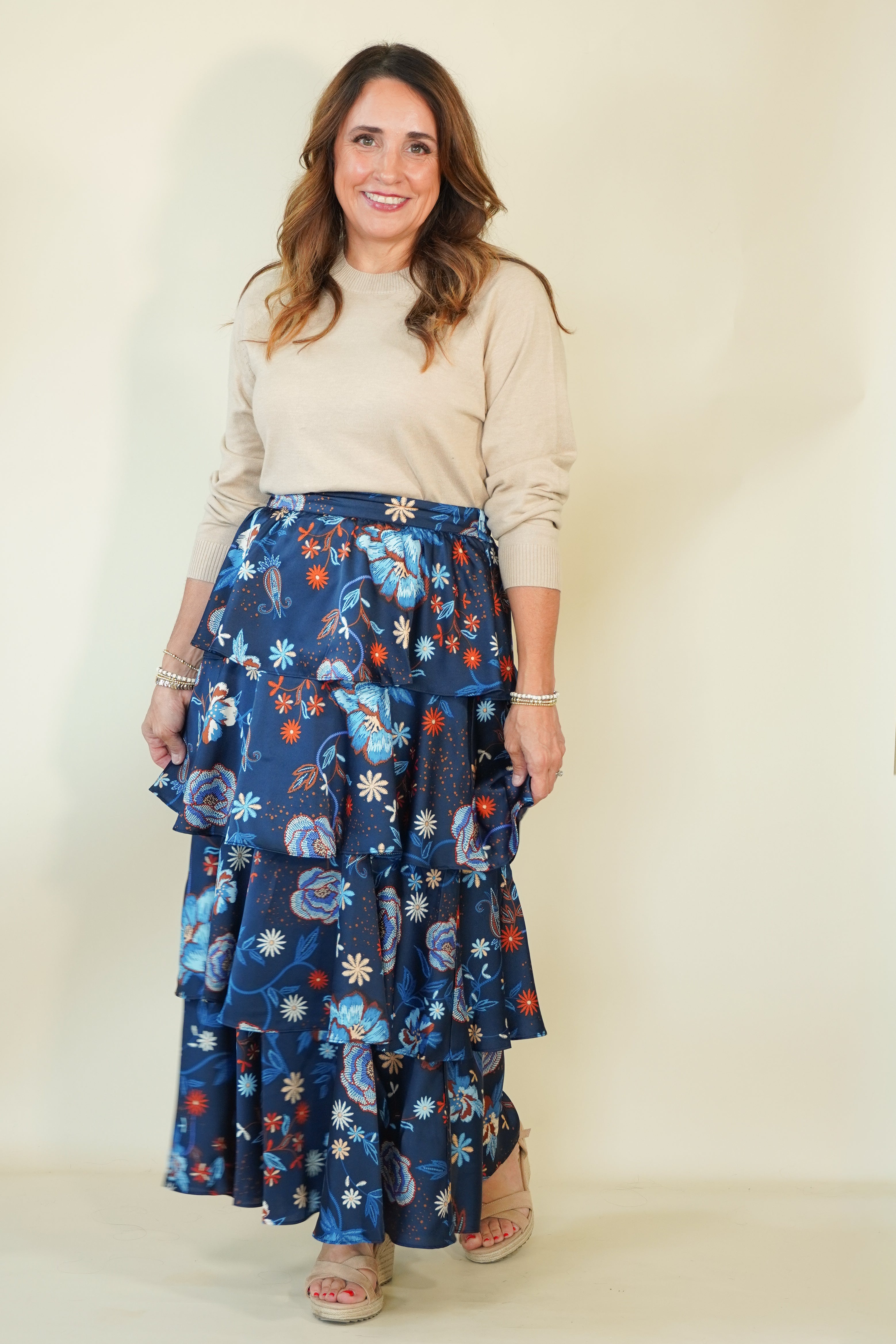 Woman wearing navy floral tiered ruffle maxi skirt with taupe top