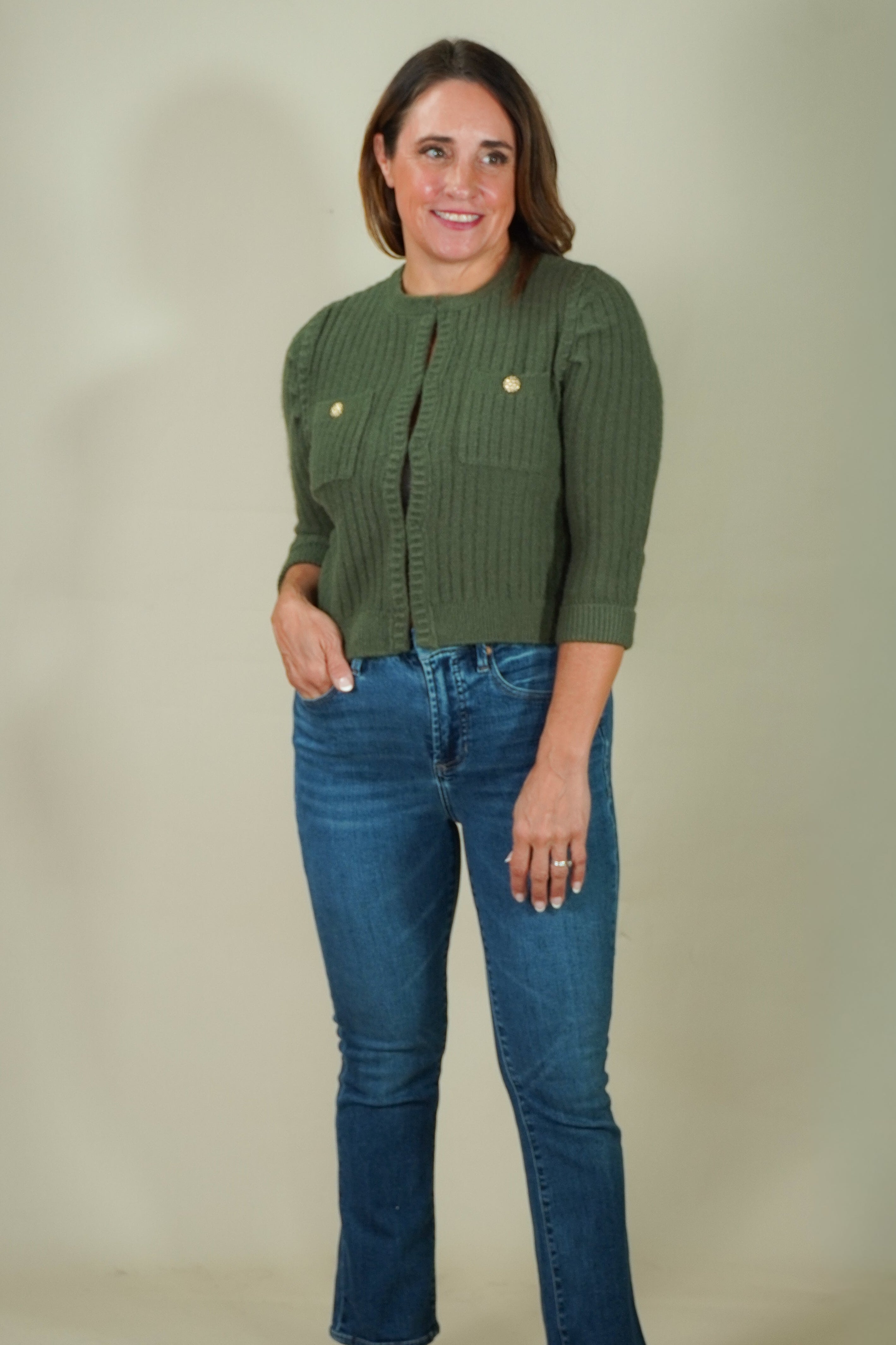 Woman wearing olive ribbed flap pocket cardigan with jeans