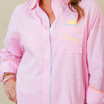 Woman wearing a pink dress with a brand logo on a beige background