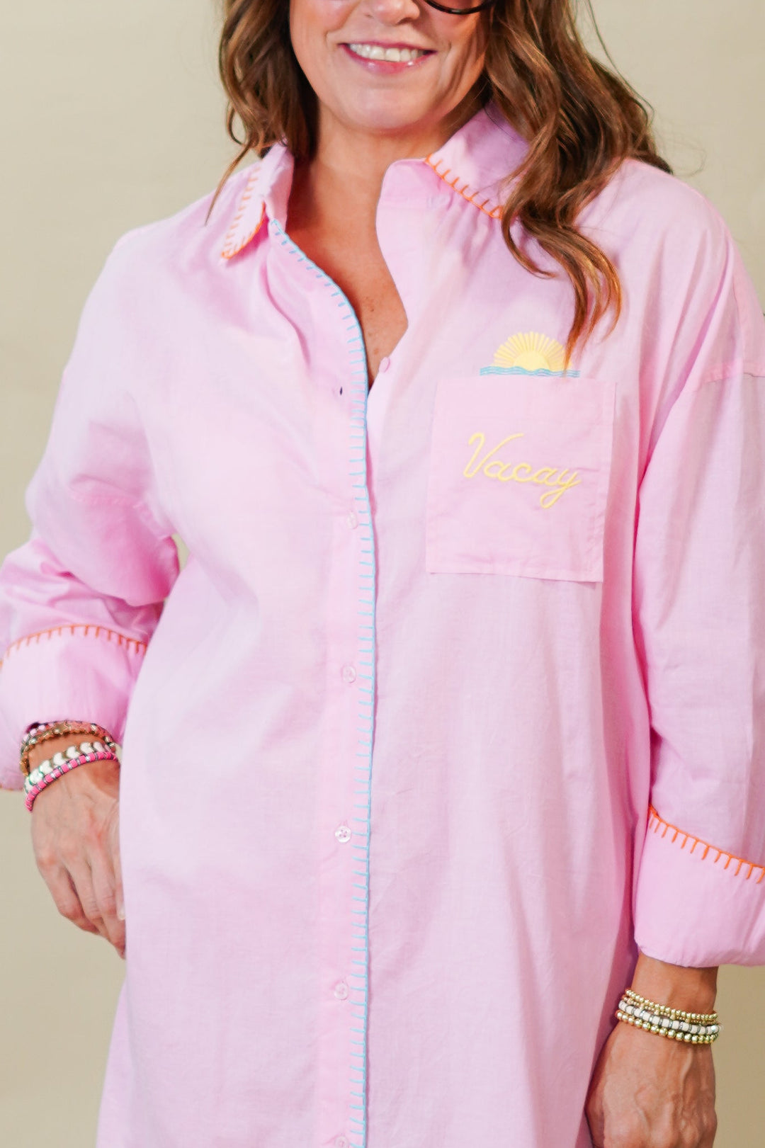 Woman wearing a pink dress with a brand logo on a beige background