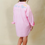 Person wearing a pink dress with text on the back against a beige background