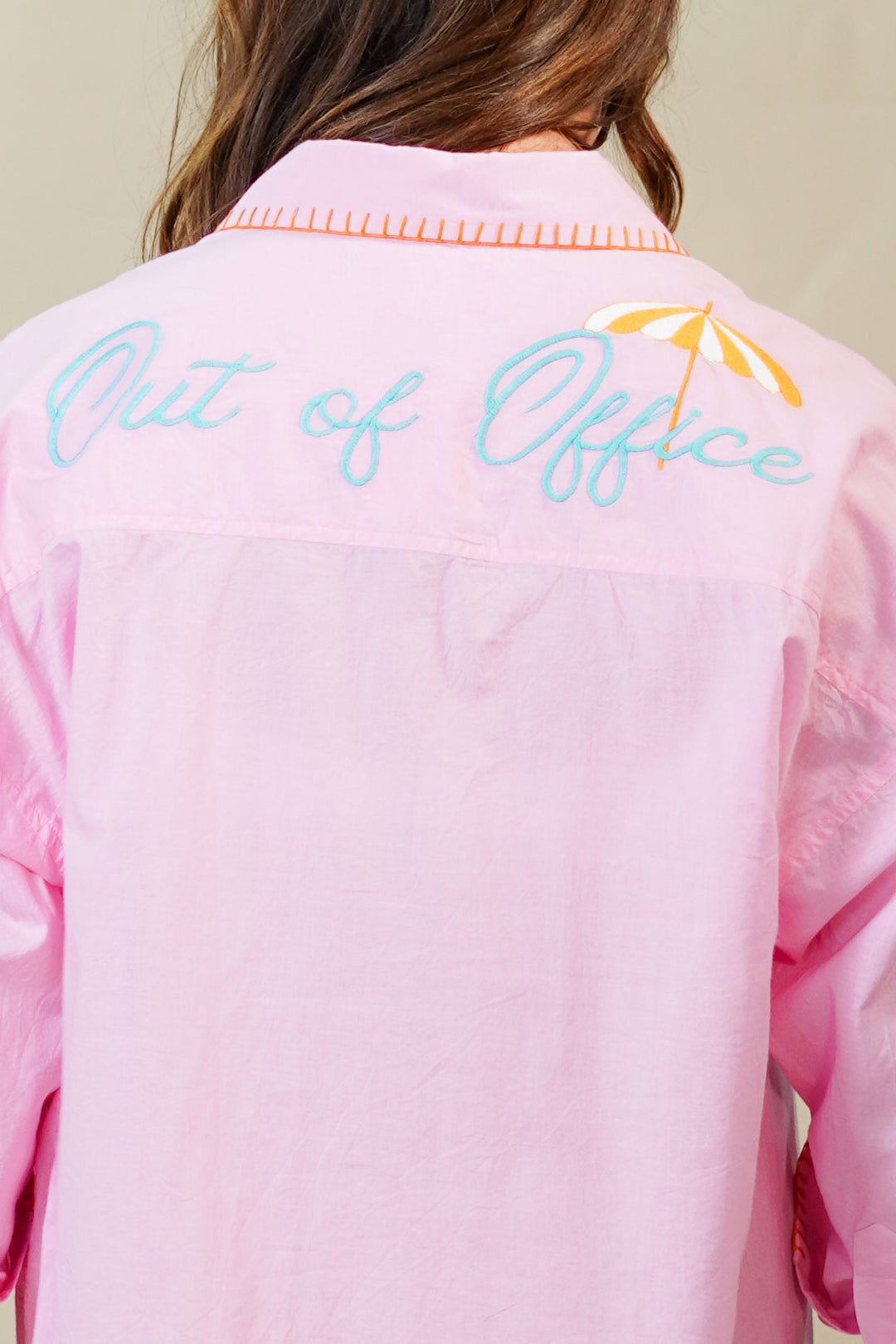 Person wearing a pink dress with text and graphics on the back against a plain background