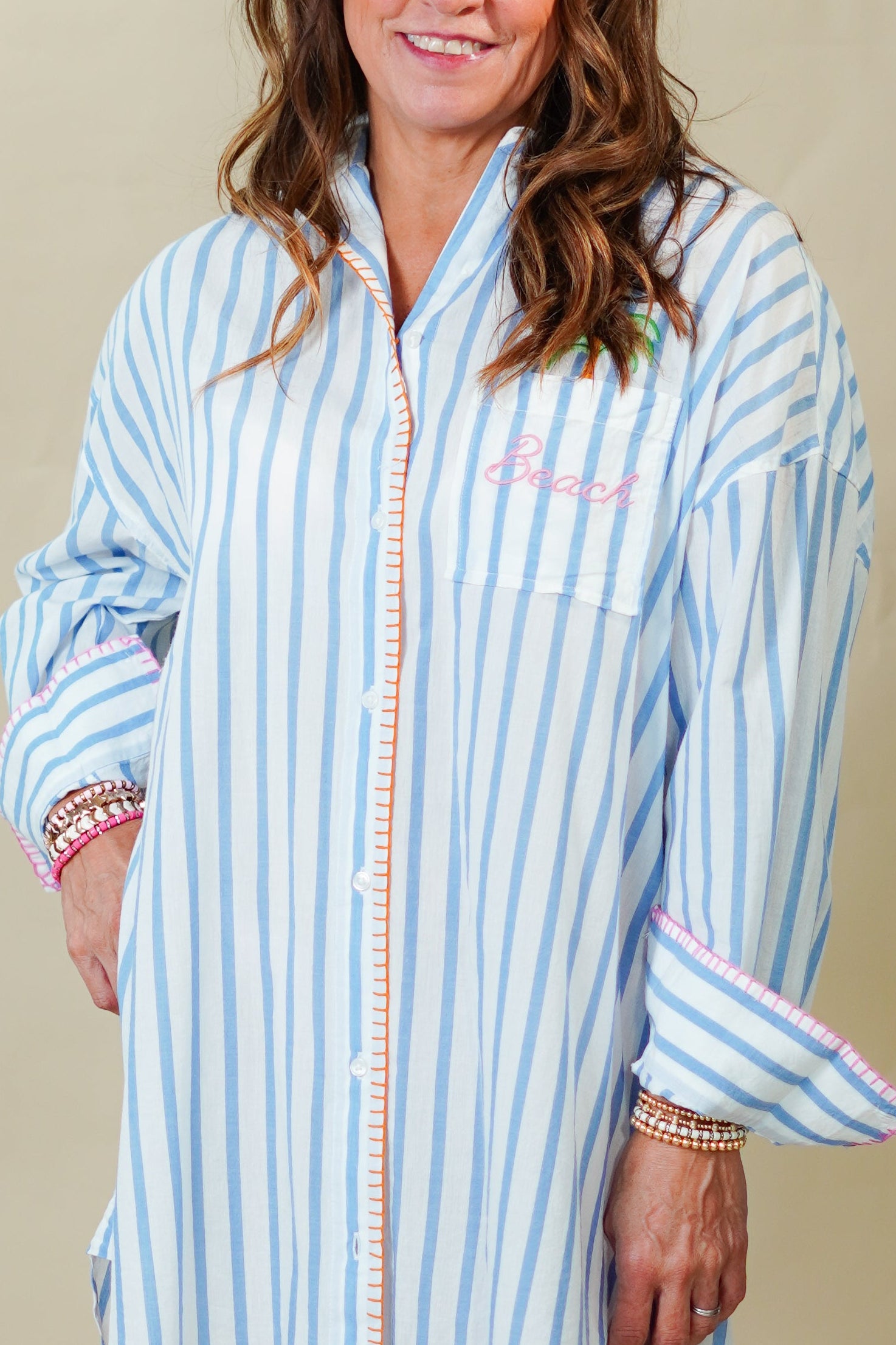 Woman wearing a blue and white striped dress against a beige background