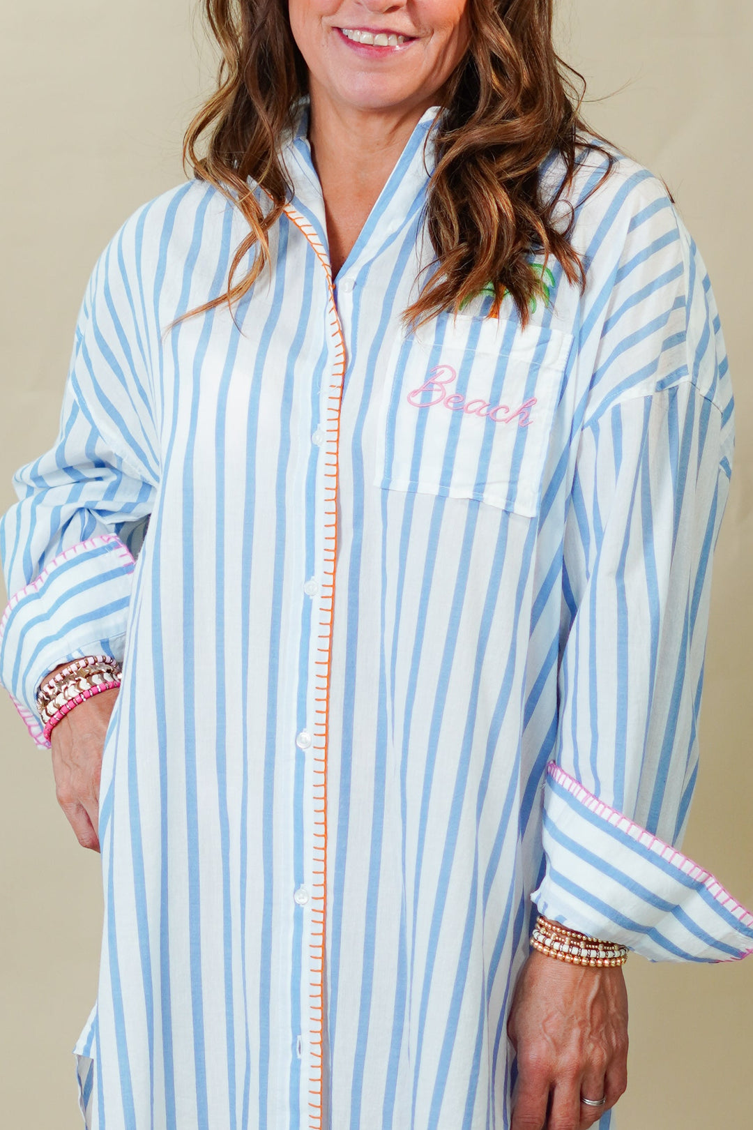 Woman wearing a blue and white striped dress against a beige background