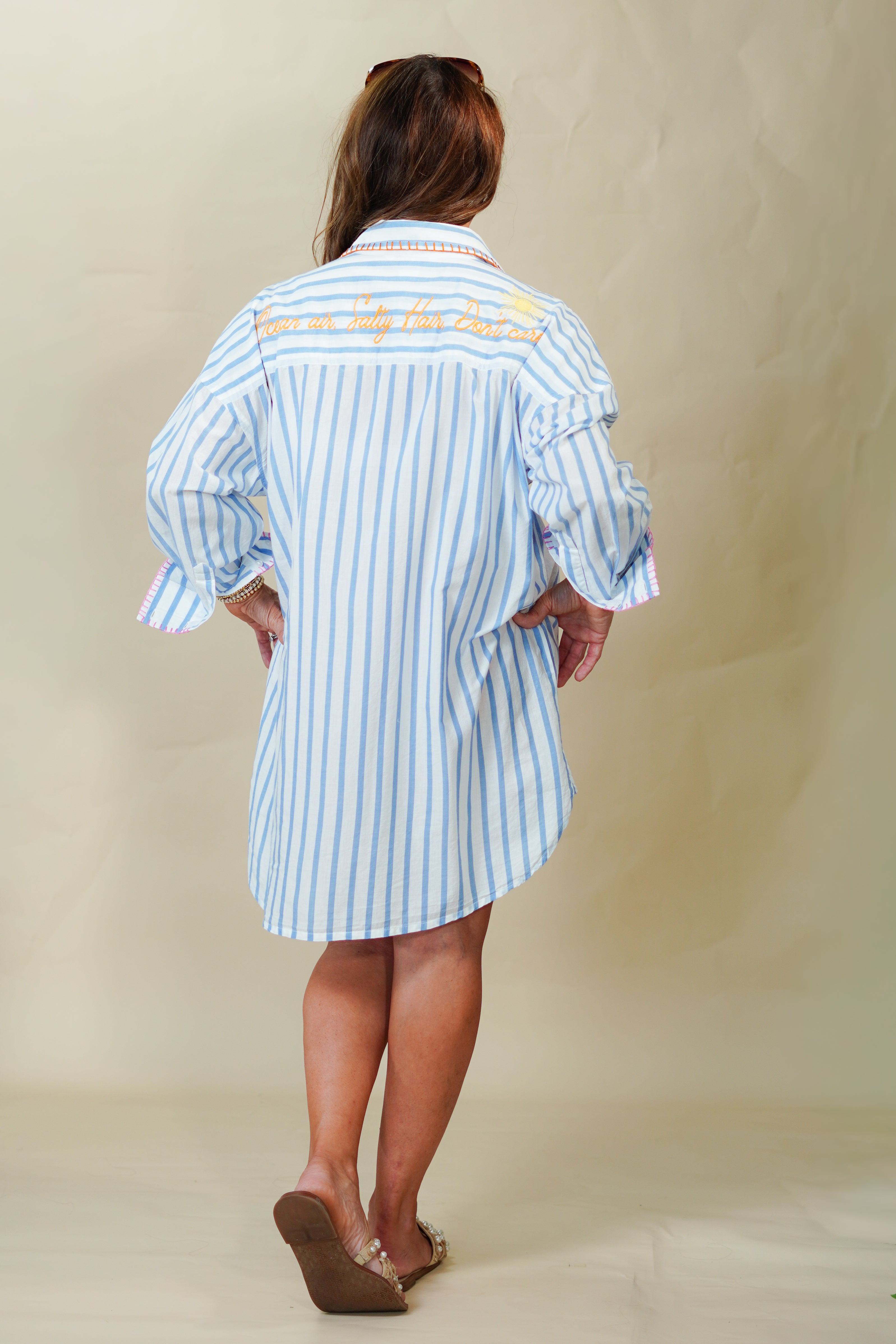 Person wearing a blue and white striped dress with text on a plain background