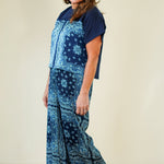 Woman wearing a blue patterned outfit on a beige background