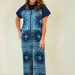 Woman wearing a blue patterned jumpsuit on a beige background