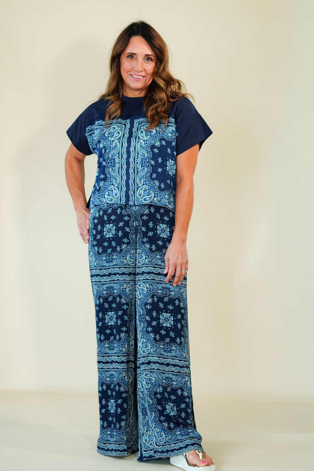 Woman wearing a blue patterned jumpsuit on a beige background