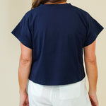 Person wearing a navy blue top and white shorts on a beige background