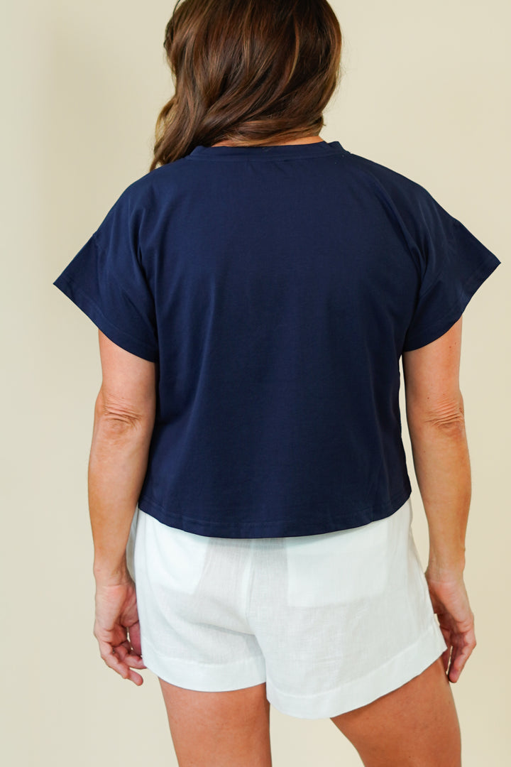 Person wearing a navy blue top and white shorts on a beige background
