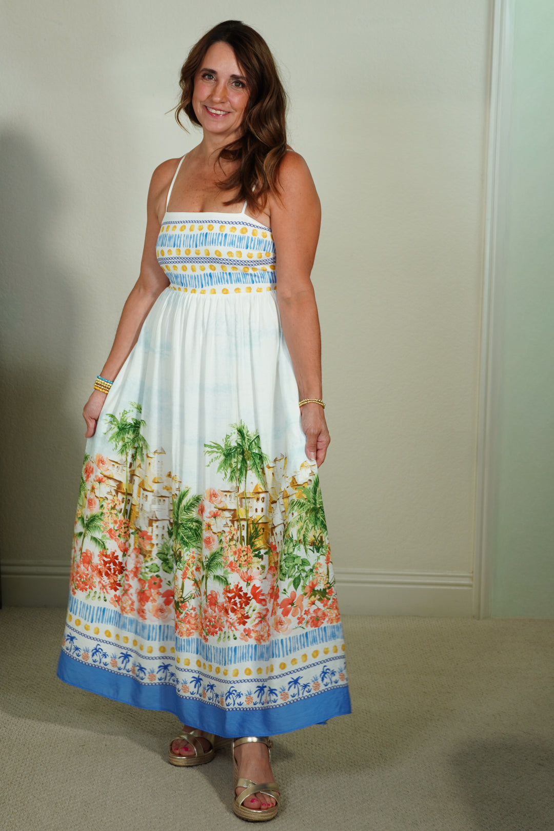 Woman wearing a colorful dress with palm tree and floral pattern indoors.