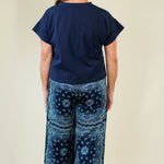 Person wearing a navy blue top and patterned blue pants on a beige background