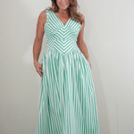 Woman wearing a green and white striped dress against a plain background