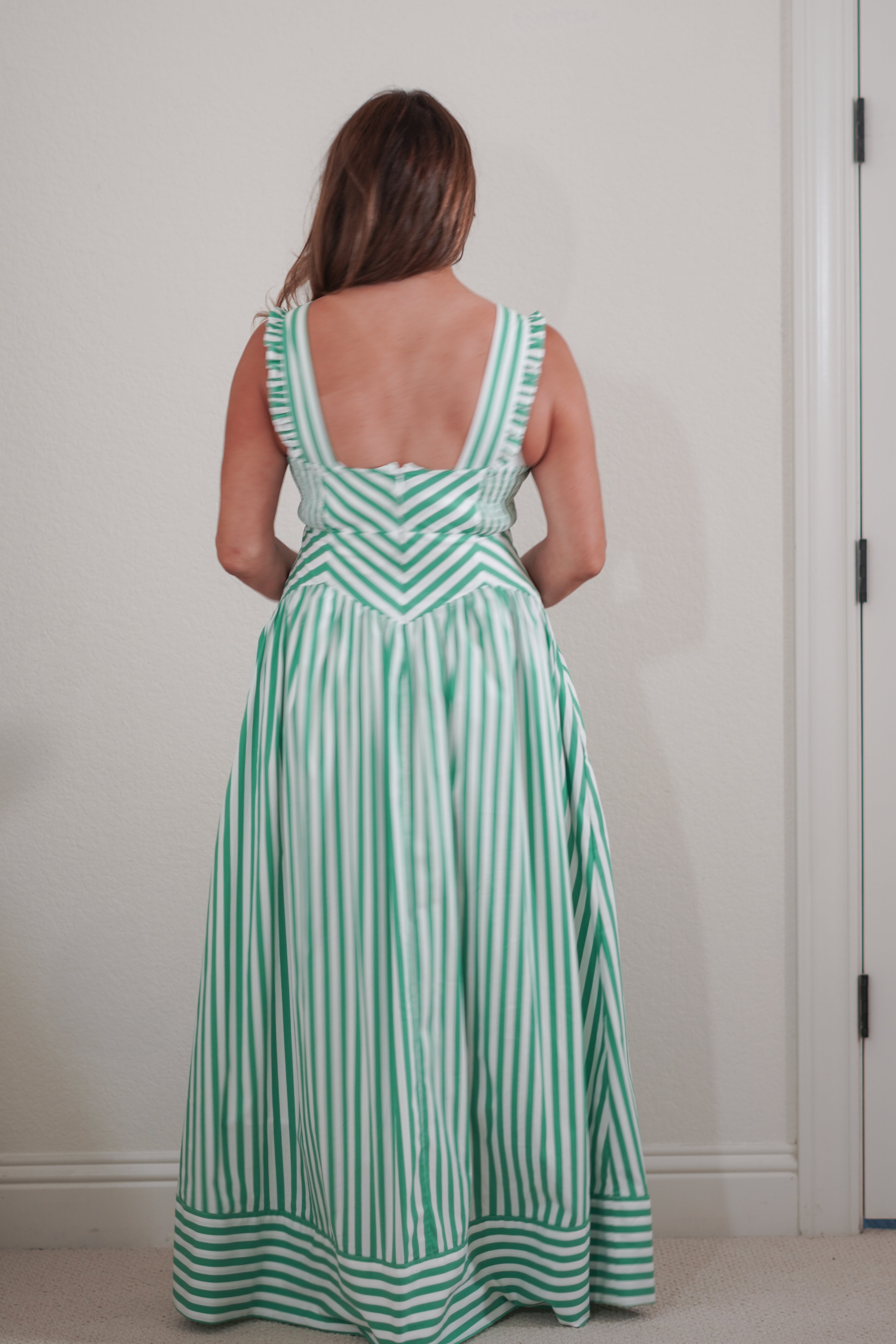 Woman wearing a green and white striped dress against a plain background