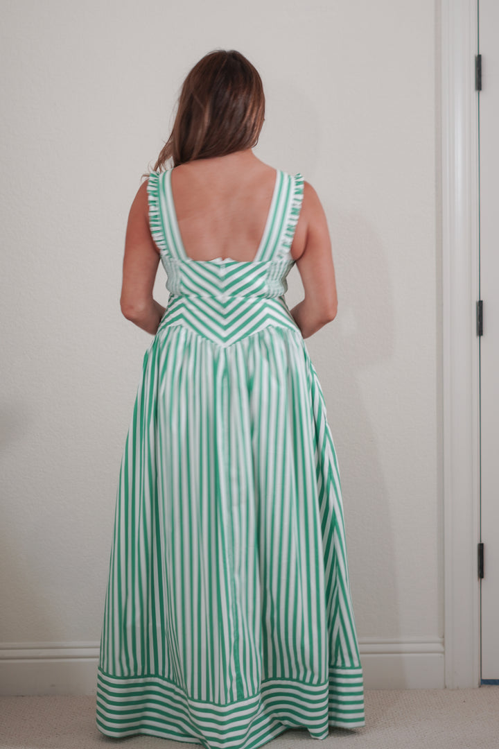 Woman wearing a green and white striped dress against a plain background