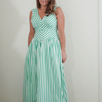 Woman wearing a green and white striped dress against a plain background