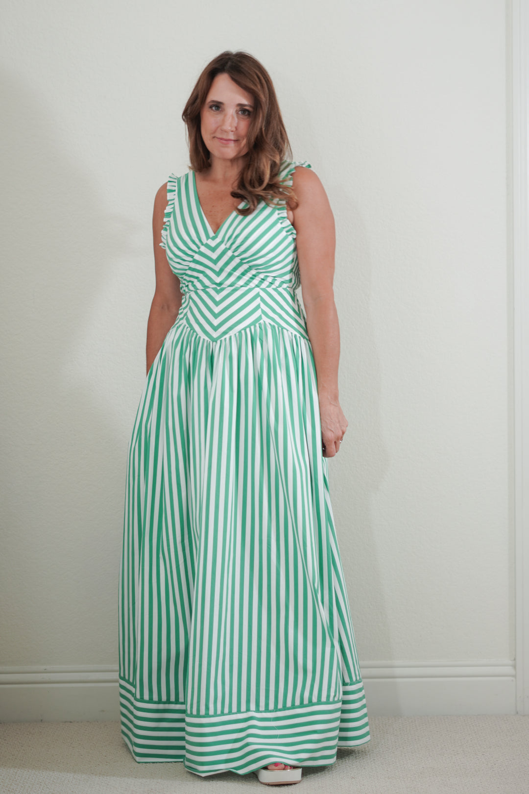 Woman wearing a green and white striped dress against a plain background