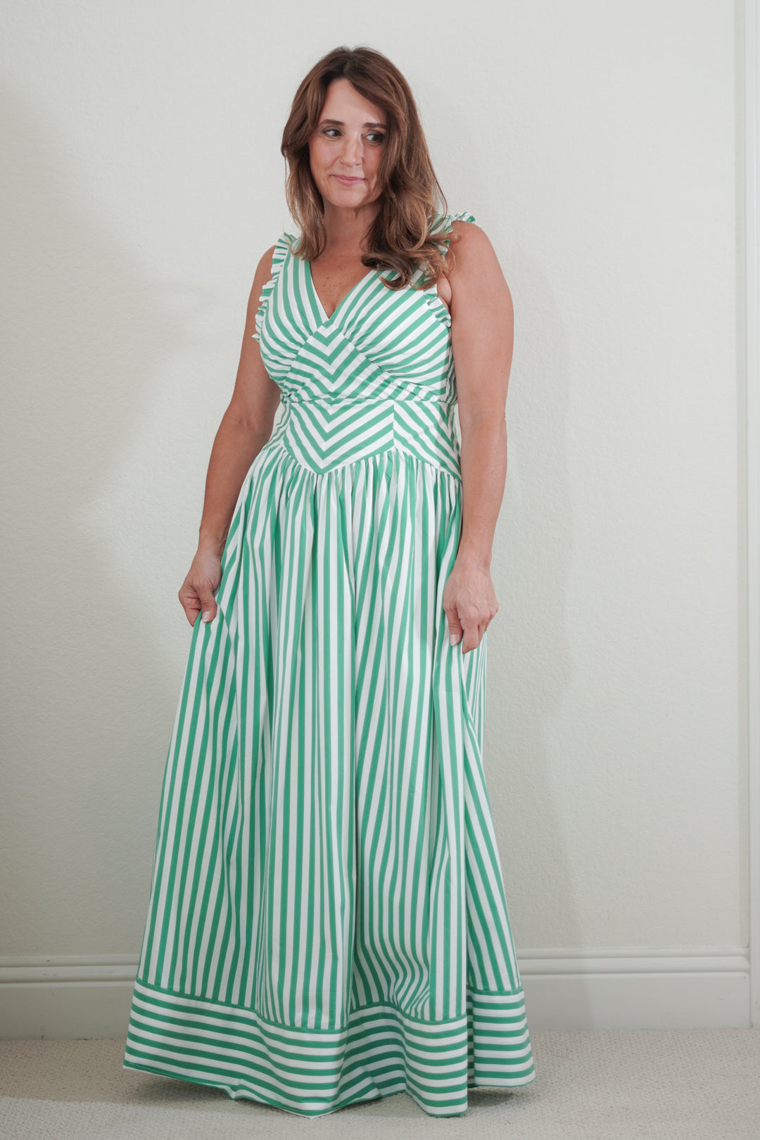 Woman wearing a green and white striped dress against a plain background