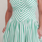 Woman wearing a green and white striped dress against a plain background