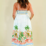 Woman wearing a floral dress with palm trees on a plain background