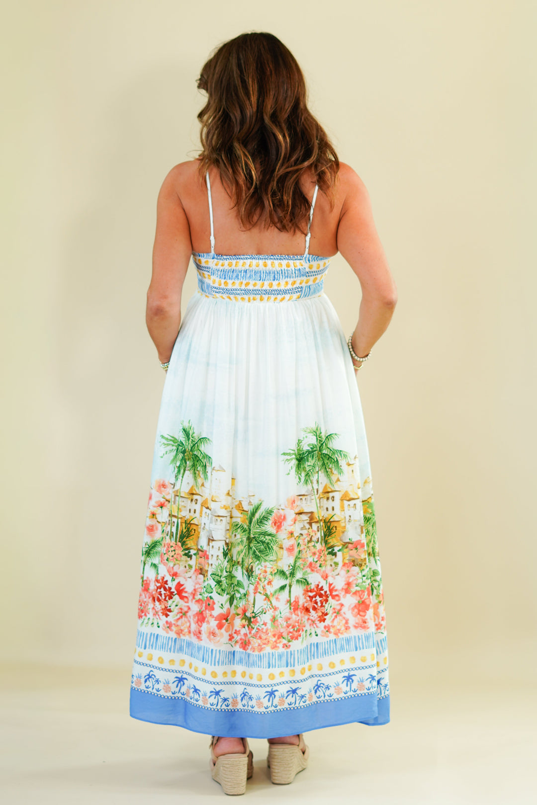 Woman wearing a floral dress with palm trees on a plain background