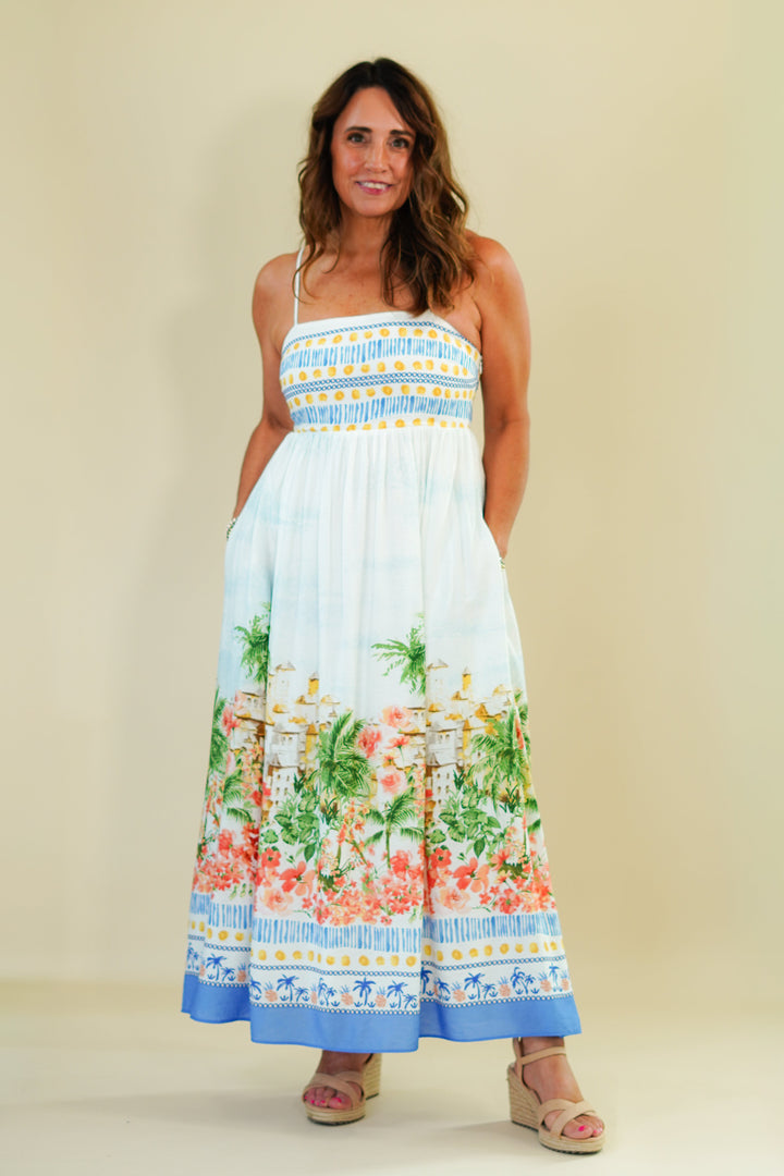 Woman wearing a colorful dress with floral and palm tree pattern on a beige background