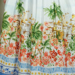 Woman wearing a colorful dress with a scenic print indoors.