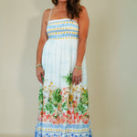 Woman wearing a colorful floral dress against a plain background